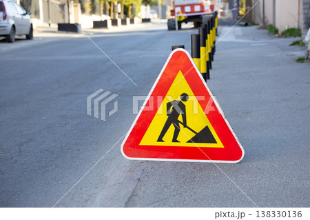 Road work warning sign standing on a residential street. Repair, caution, infrastructure, maintenance, disruption, safety, and temporary traffic control in an everyday urban environment Road work warning sign standing on a residential street. Repair, caution, infrastructure, maintenance, disruption, safety, and temporary traffic control in an everyday urban environment 138330136