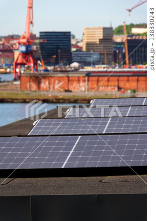 Solar panels on roof of apartment housing building with Gothenburg city center in background, Sweden, renewable green sustainable energy concept 138330243