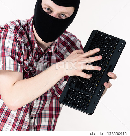 Man wearing balaclava holding keyboard Man wearing balaclava holding keyboard 138330413