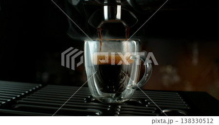 Fresh espresso pouring from coffee machine into glass cup with rich crema and rising steam. Warm cinematic scene capturing preparation of black coffee in cozy atmosphere. Fresh espresso pouring from coffee machine into glass cup with rich crema and rising steam. Warm cinematic scene capturing preparation of black coffee in cozy atmosphere. 138330512