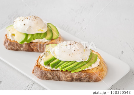 Avocado toast with poached eggs on artisan bread plate Avocado toast with poached eggs on artisan bread plate 138330548