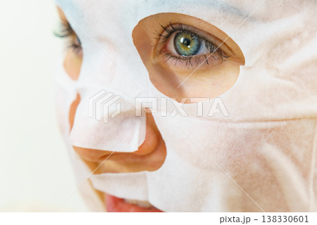 Woman applying sheet mask on face 138330601