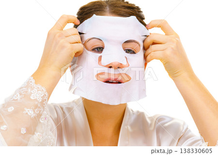 Woman applying sheet mask on face Woman applying sheet mask on face 138330605