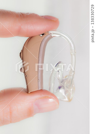 senior person holding hearing aid closeup senior person holding hearing aid closeup 138330729