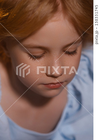 Close up portrait of redhead girl with freckles looking down, soft light studio background 138331745