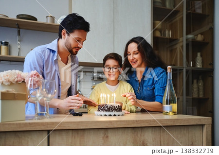 Family celebration with cake and candles in cozy home kitchen setting Family celebration with cake and candles in cozy home kitchen setting 138332719