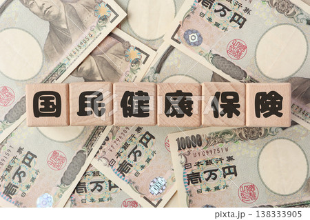 国民健康保険と保険料負担のイメージ・木製ブロック文字・1万円札 国民健康保険と保険料負担のイメージ・木製ブロック文字・1万円札 138333905