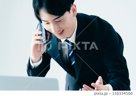 オフィスで電話する若いビジネスマン オフィスで電話する若いビジネスマン 138334500