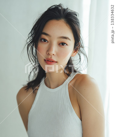 白いタンクトップを着た、ツヤ肌と無造作ヘアの若い女性のポートレート 138334632