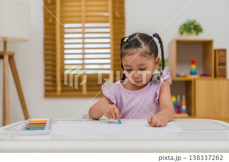 preschool child girl drawing and painting with colorful oil pastels on paper 138337262