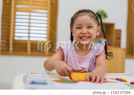 happy preschool child girl drawing and painting with colorful oil pastels on paper 138337266