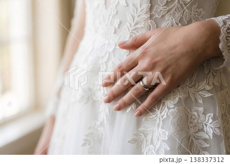 ウェディングドレスのレースに触れる花嫁の結婚指輪 138337312
