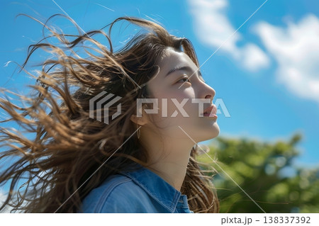 青空と新緑を背景に風に吹かれる笑顔の日本人女性　初夏の爽やかなイメージ 138337392
