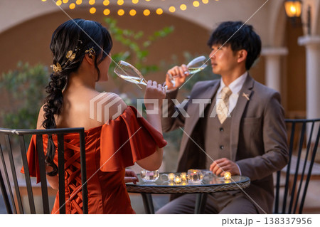 ナイトウェディング,ディナーでシャンパンを飲むドレスコードしたカップル ナイトウェディング,ディナーでシャンパンを飲むドレスコードしたカップル 138337956
