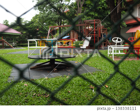 Playground empty fenced grass outdoor daytime slide swing park childhood Playground empty fenced grass outdoor daytime slide swing park childhood 138338111