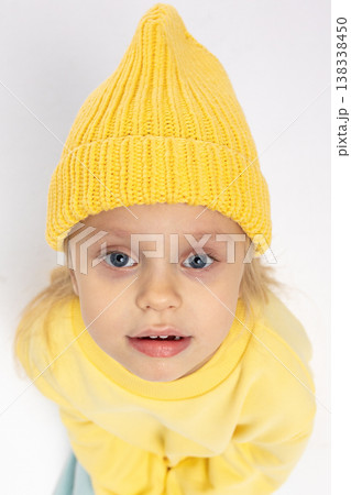 Portrait of beautiful cute little toddler girl. Child with funny face in yellow sweatshirt and yellow hat. Pretty smile kid in studio on white background. High quality photo Portrait of beautiful cute little toddler girl. Child with funny face in yellow sweatshirt and yellow hat. Pretty smile kid in studio on white background. High quality photo 138338450