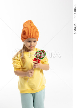 Portrait of funny little blonde girl with sweets lollipop in her hand. High quality photo 138338609