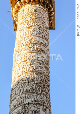 Tall ancient stone Column of Marcus Aurelius with statue on top rising above city square with historic buildings and traffic in Rome under clear blue sky, Rome, Italy Tall ancient stone Column of Marcus Aurelius with statue on top rising above city square with historic buildings and traffic in Rome under clear blue sky, Rome, Italy 138338702