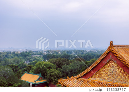 Summer Palace with golden relief patterns, orange glazed roof tiles, red wall surface and distant green landscape under hazy sky, Beijing, China 138338757