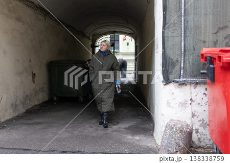 Mature woman walking on city sidewalk during autumn near residential architecture. Mature woman walking on city sidewalk during autumn near residential architecture. 138338759