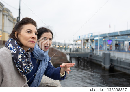 Female friends observing port area and talking outdoors near river embankment, urban lifestyle and travel concept.  138338827