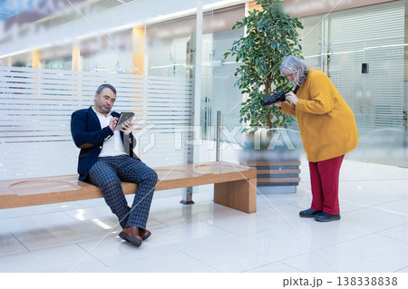 Female photographer shooting a businessman reading an ebook in a bright modern office. High quality photo Female photographer shooting a businessman reading an ebook in a bright modern office. High quality photo 138338838