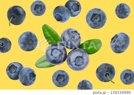 Blueberries with green leaves placed on a bright yellow surface Blueberries with green leaves placed on a bright yellow surface 138338999