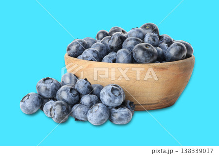 Blueberries sit in a wooden bowl with some outside Blueberries sit in a wooden bowl with some outside 138339017