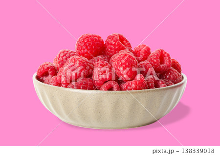 Bowl full of red raspberries sits on pink surface Bowl full of red raspberries sits on pink surface 138339018