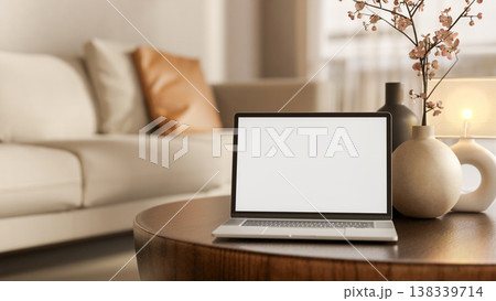 White screen laptop with flower vase and lamp on round wooden table aside sofa in modern living room 138339714