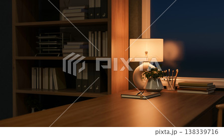Illuminating lamp with books and pencil aside potted plant on wooden table aside shelf in dim office 138339716