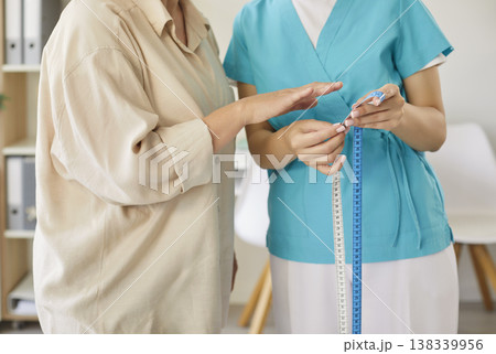 Senior woman waist measurement by nurse during clinic checkup and consultation 138339956