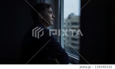 窓から外を眺めて天気を気にしている男性 138340320