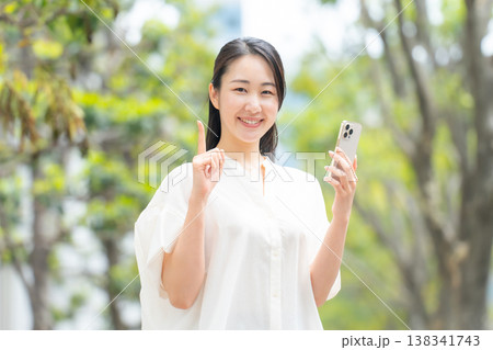 女性　カジュアル　初夏　スマホ　指差し 138341743