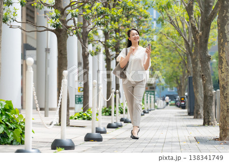 女性　カジュアル　初夏　歩く　スマホ 138341749