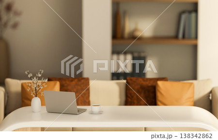 Laptop and coffee with flower vase on white table and sofa across wooden bookshelf in a living room. Laptop and coffee with flower vase on white table and sofa across wooden bookshelf in a living room. 138342862