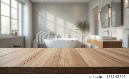 Empty wooden table foreground with a blurred, bright interior of a luxury modern bathroom featuring a white soaking tub and double vanity. Empty wooden table foreground with a blurred, bright interior of a luxury modern bathroom featuring a white soaking tub and double vanity. 138342891