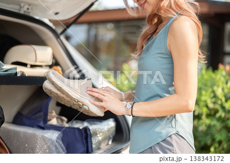 Close up of woman in sportswear holding sneakers standing aside car going to exercise at gym fitness 138343172