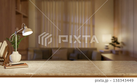 Desk lamp with book and pencils aside potted plant on marble counter table across window in dim room 138343449