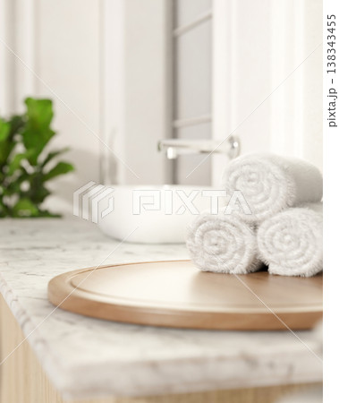 White towels on round wooden tray at marble sink counter aside houseplant in bright modern bathroom White towels on round wooden tray at marble sink counter aside houseplant in bright modern bathroom 138343455