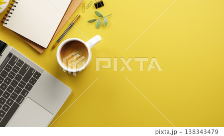 Top view of laptop with coffee and blank notebook aside pen and binder clip on yellow table surface. 138343479