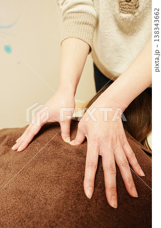 肩の母指圧をする女性セラピストの手元(逆角度からの撮影) 肩の母指圧をする女性セラピストの手元(逆角度からの撮影) 138343662