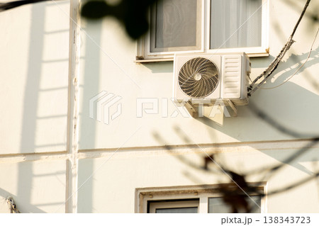 air conditioner is installed on facade of the building. air conditioner compressor is on wall. air conditioner is installed on facade of the building. air conditioner compressor is on wall. 138343723