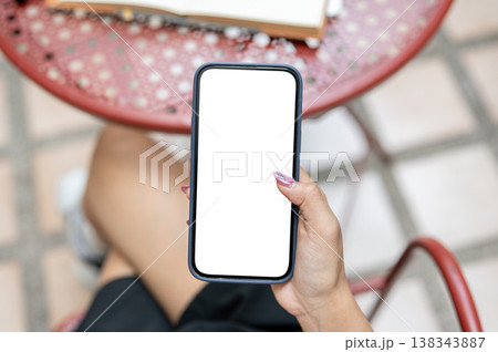 Top view of woman's hand holding white screen phone using social media reading news at outdoor table Top view of woman's hand holding white screen phone using social media reading news at outdoor table 138343887