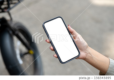 Top view of woman's hand holding white screen smartphone standing on street or pavement with bicycle Top view of woman's hand holding white screen smartphone standing on street or pavement with bicycle 138343895