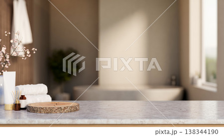Skincare and diffuser aside tree stump tray and towel on marble counter across tub in dim bathroom. 138344190