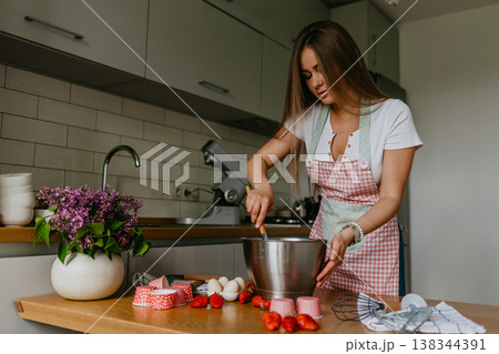 Young woman with confectionery bag squeezing cream on cupcakes 138344391