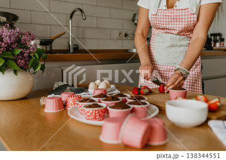 Young woman decorating cupcakes in bright kitchen Young woman decorating cupcakes in bright kitchen 138344551