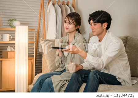 夜にリビングのソファに座りテレビを見る夫婦 夜にリビングのソファに座りテレビを見る夫婦 138344725