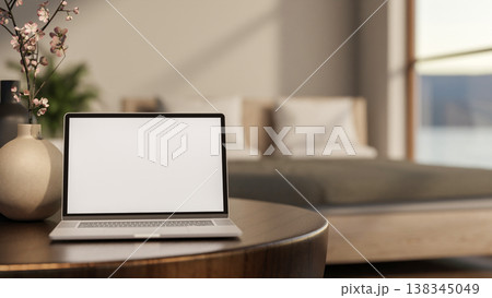 White screen laptop and flower vase on round wooden table with sunlight through window in the bedroom White screen laptop and flower vase on round wooden table with sunlight through window in the bedroom 138345049